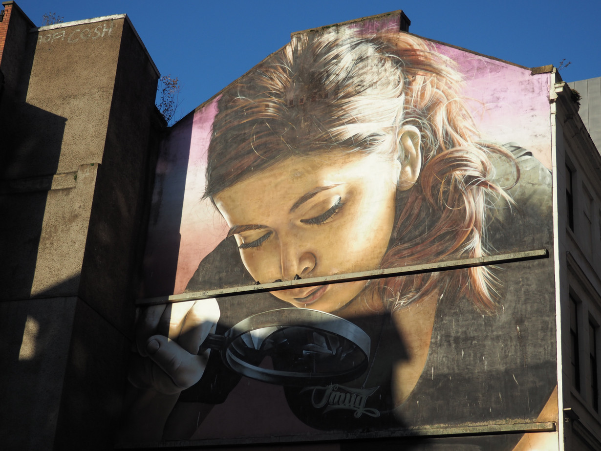 Very detailed mural of a woman looking through a magnifier.
